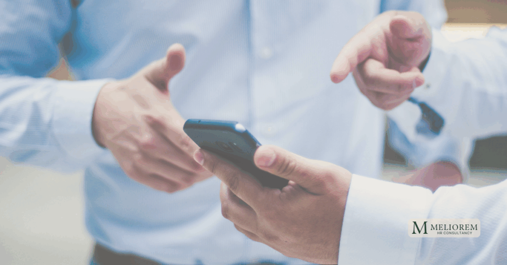 Two people having a conversation and pointing at a phone. Making a hiring decision.