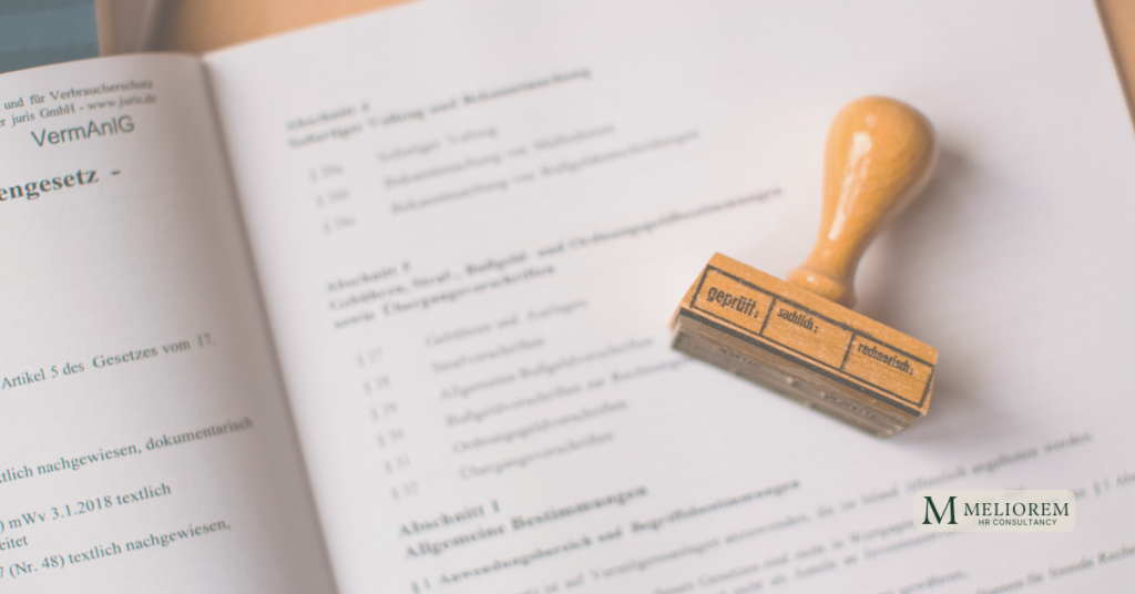 A rubber stamp pressed onto a formal contract document, symbolising the bureaucratic process culture that defines tantric HR