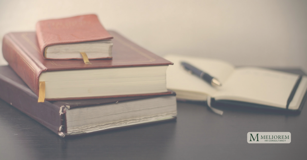 stack of legal reference books on a table beside an open notepad and pen, representing the Employment Rights Act 2025 and its implications for UK employers